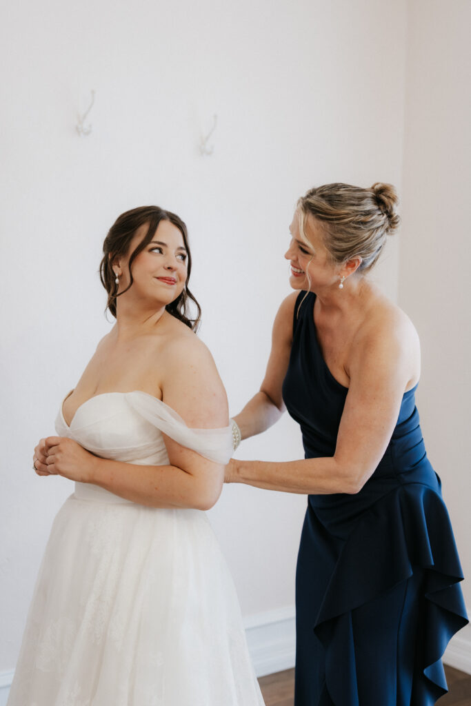 Mother of the bride helping the bride in her dress.