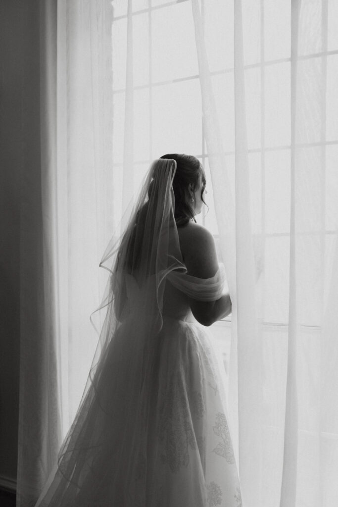 Bride looking out a window before the ceremony.
