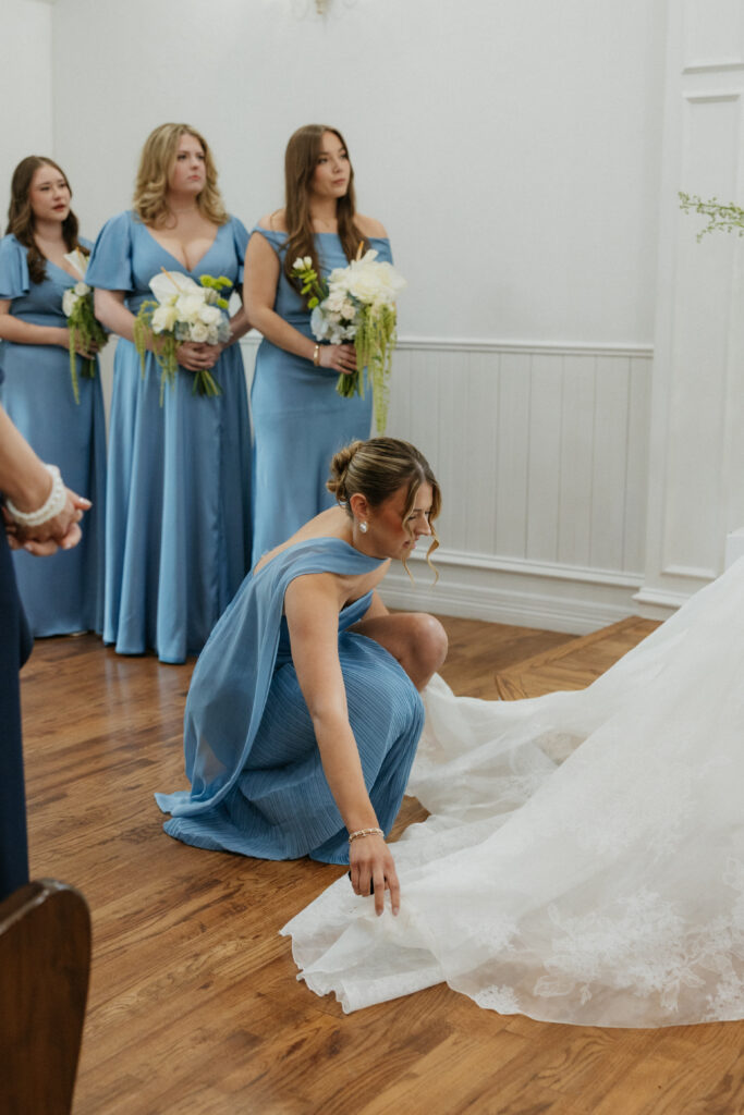 Maid of honor adjusting the train of the bride. 