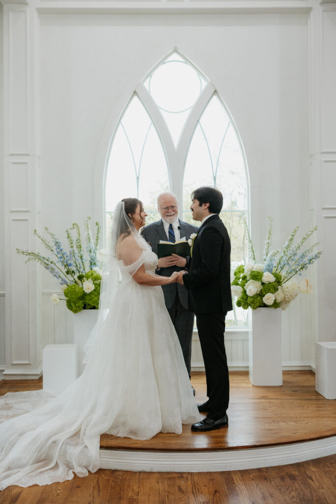 Bride and groom holding hands at the altar. 