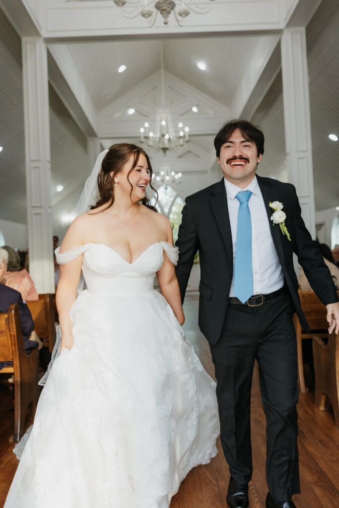 Bride and groom smiling as they exit the wedding ceremony. 