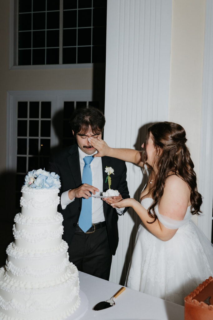 Bride putting cake on her husband's nose. 