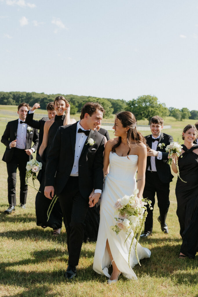 Bride and groom walking outside of their venue with their wedding party.