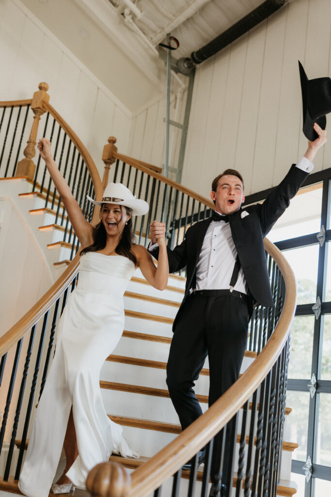 Bride and groom entering their wedding reception with their hands in the air.