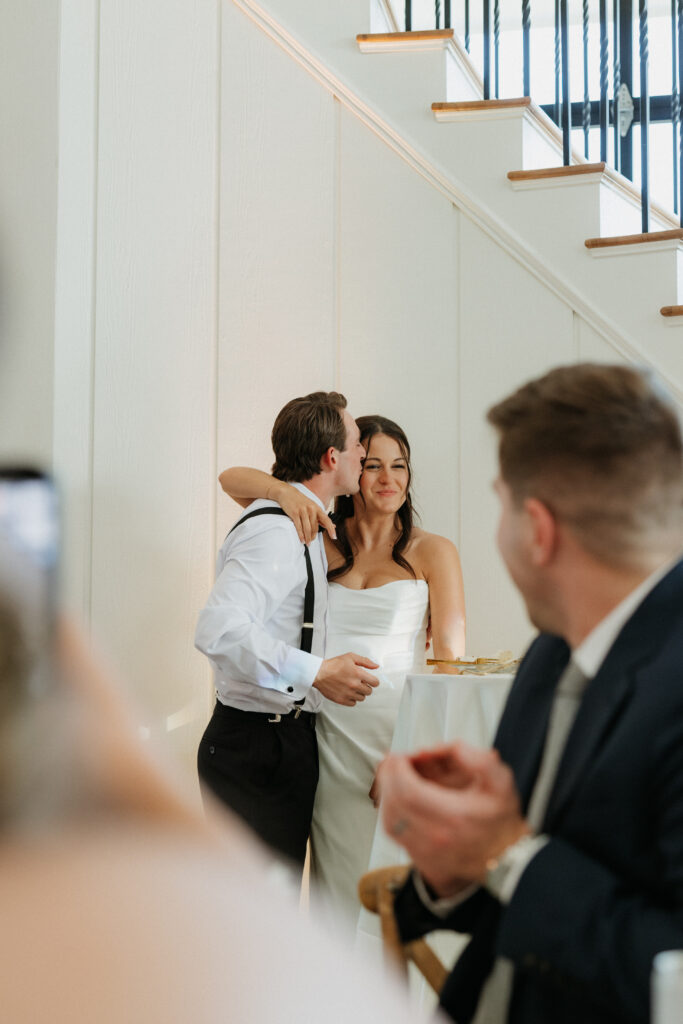 Groom kissing his bride's head during their reception.