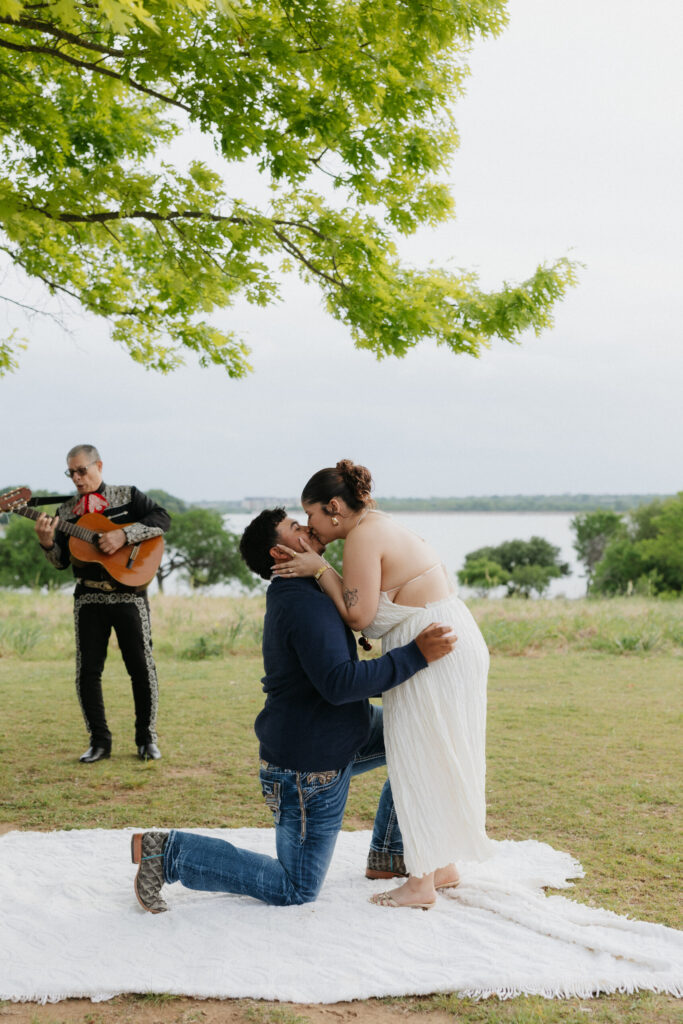 Woman kissing her boyfriend while he's on one knee proposing.