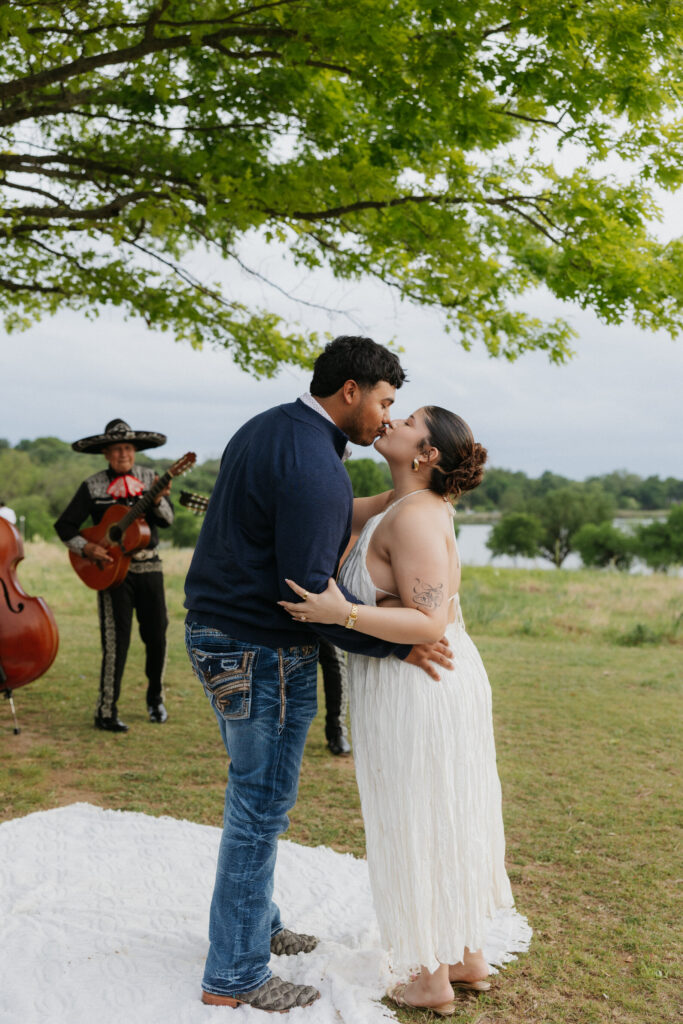Couple kissing while a mariachi band plays during their proposal.