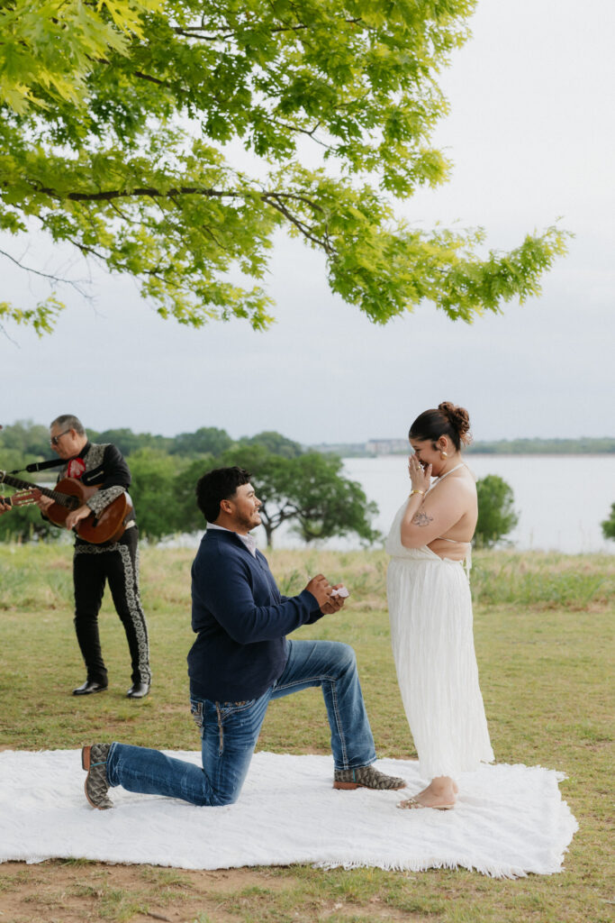 Man on one knee proposing to his girlfriend at Winfrey Point on White Rock Lake.