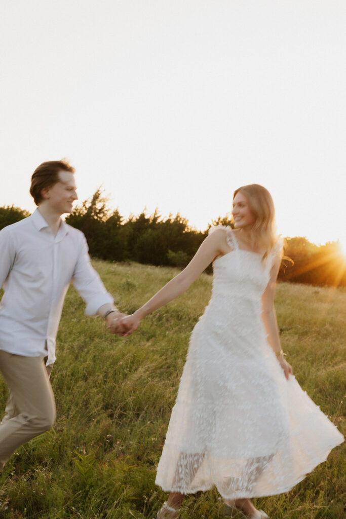 Couple playfully running in a field after their outdoor proposal ideas.