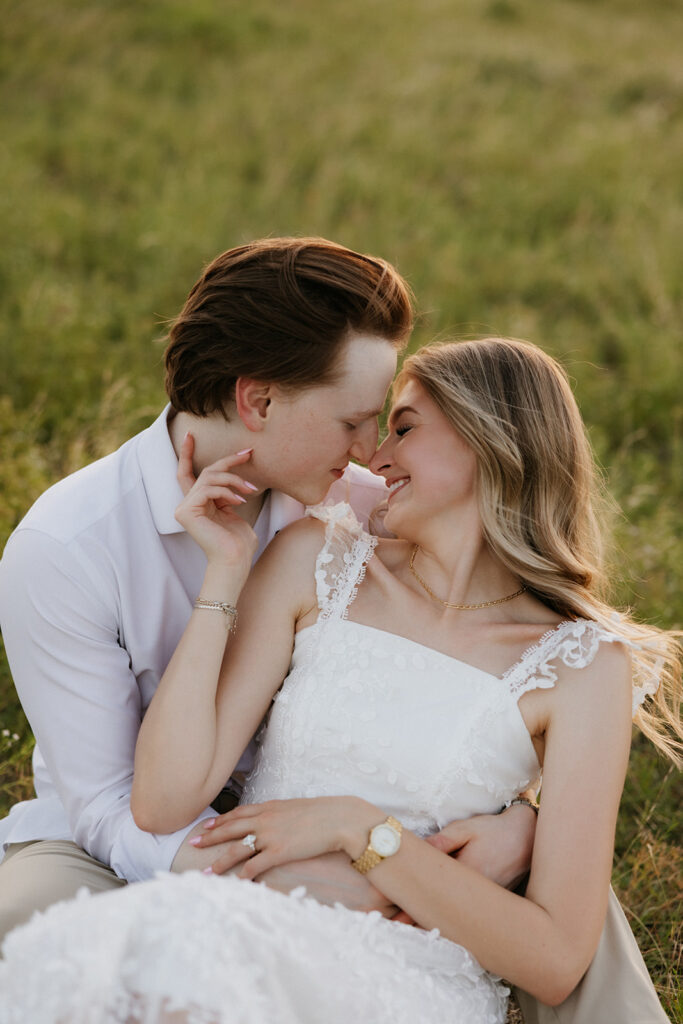 Couple sitting together in a grass field during sunset. 
