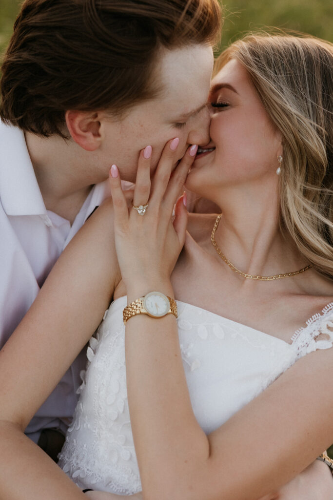 Couple kissing while sitting in a field in Dallas. 