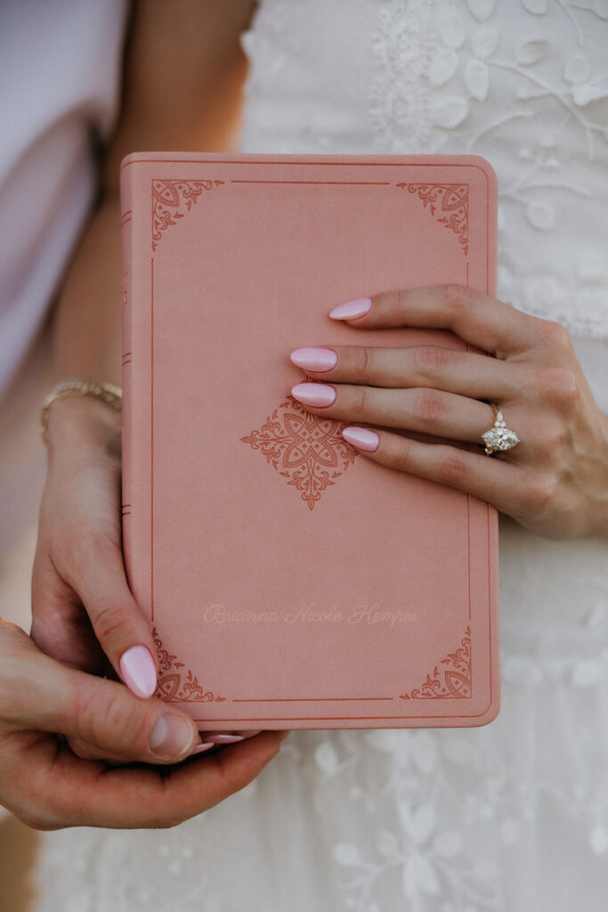 Woman holding her custom engraved Bible while wearing her engagement ring. 