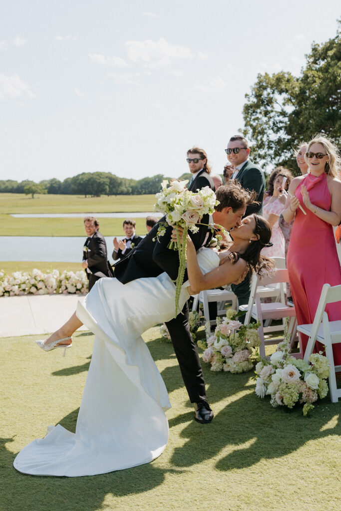 Groom dipping his bride at the end of the aisle at Bella Cavalli Events.