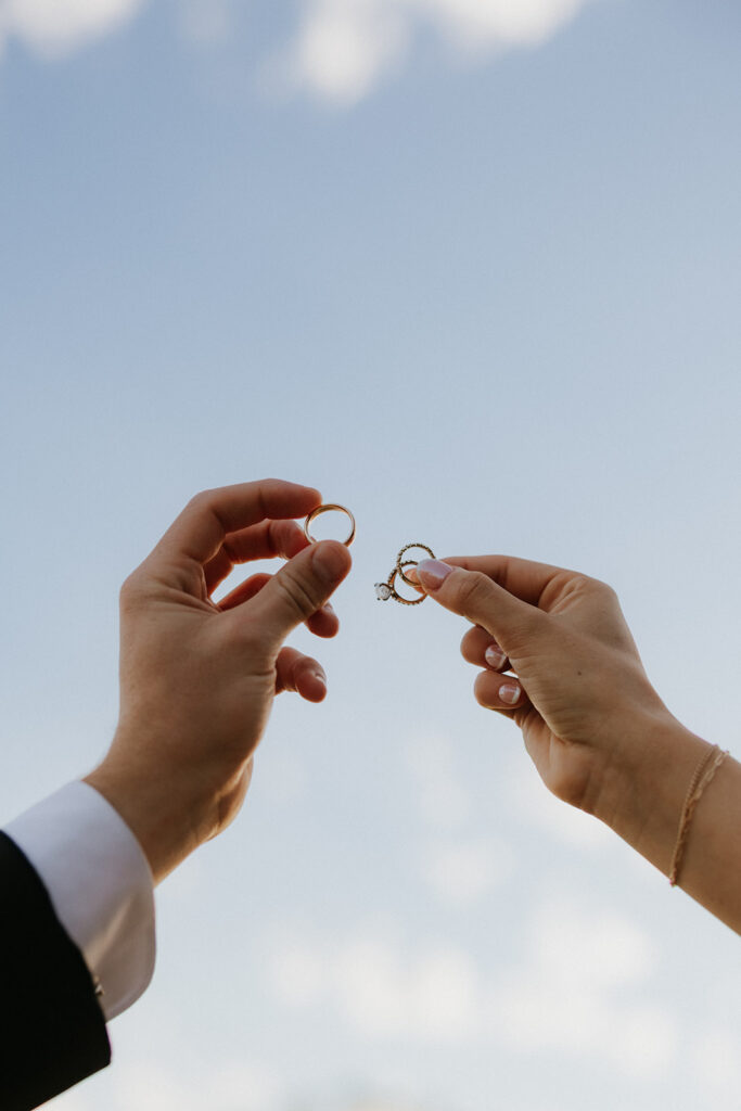 Couple holding their wedding rings in the air.