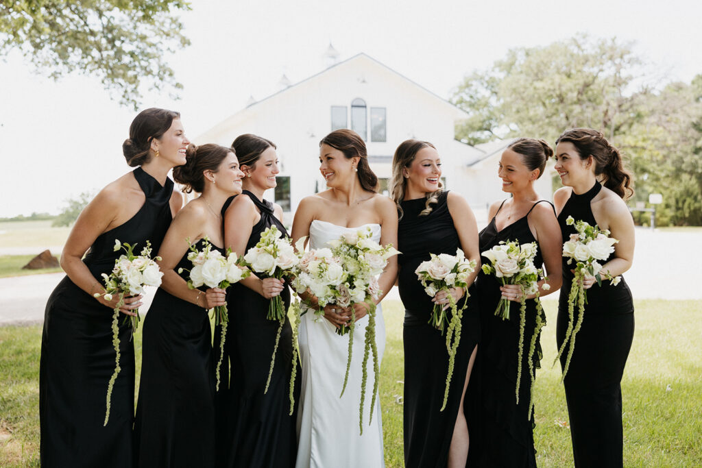 Bridal party smiling and holding spring wedding flowers.