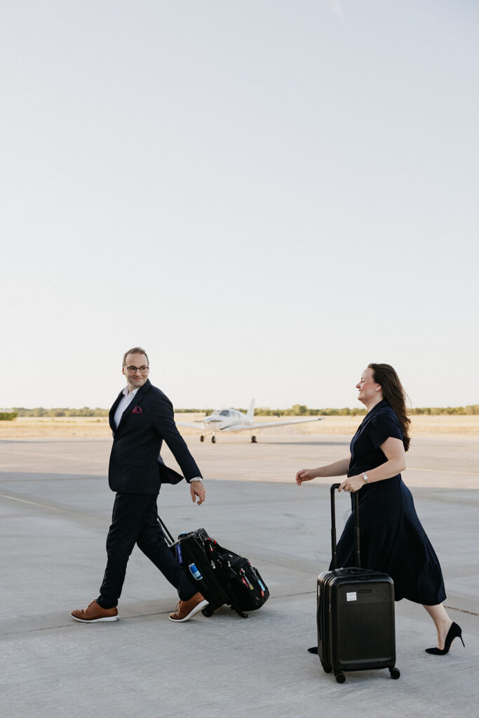 Couple walking while rolling suitcases at an airport in Dallas.
