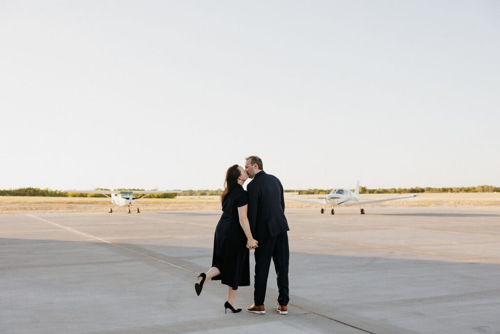 Couple kissing with two planes in front of them.
