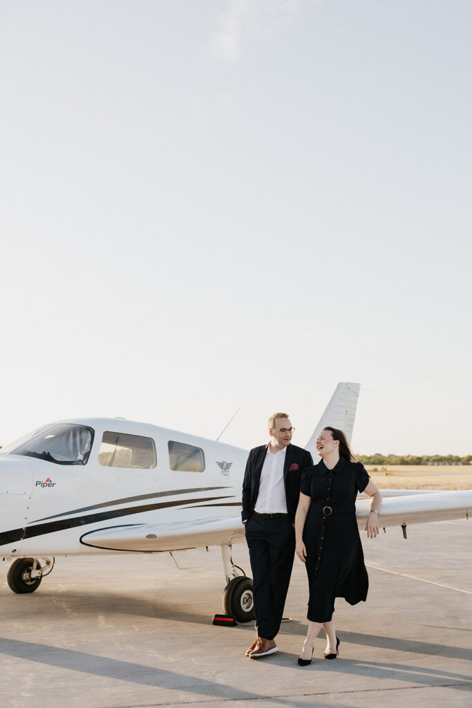 Couple looking at one another while leaning against an airplane during their airplane photoshoot.