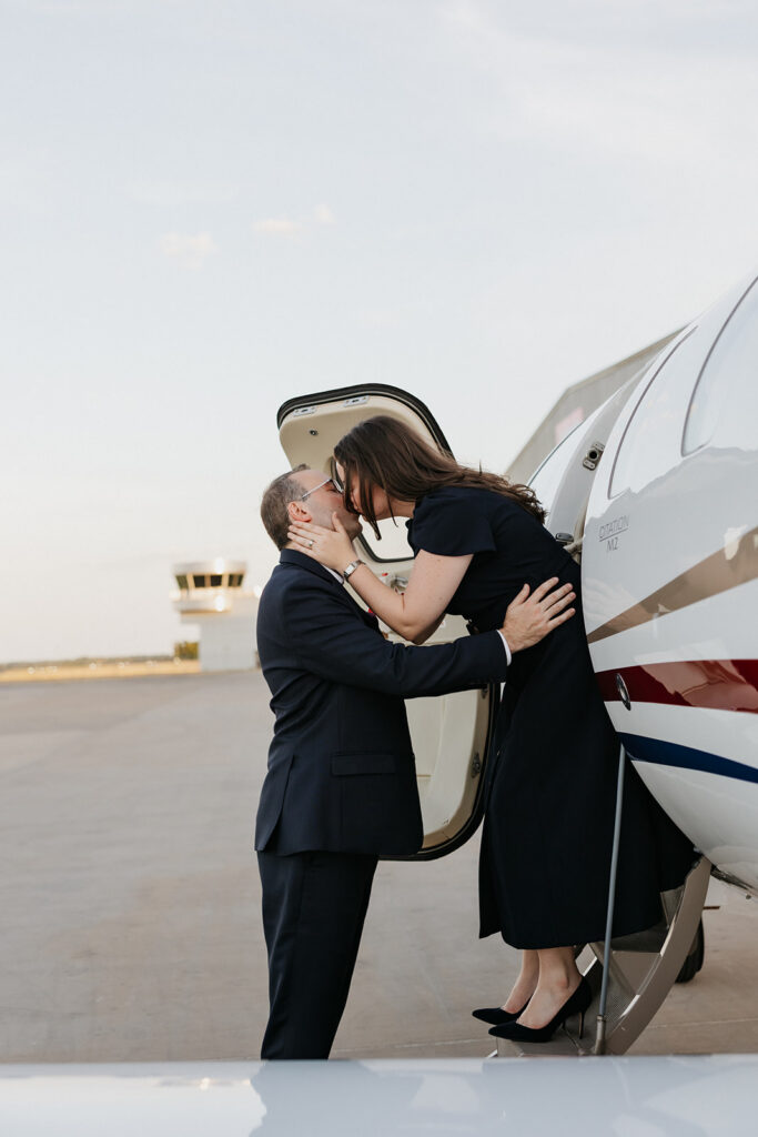 Airplane photoshoot of a couple kissing on the steps to a private jet. 