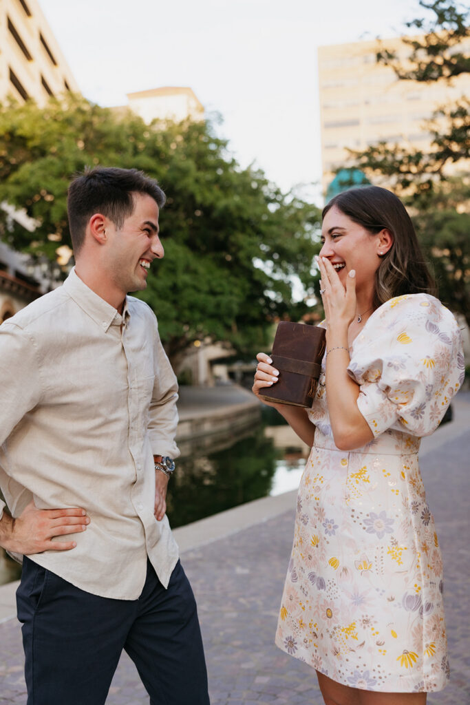 Newly engaged couple smiling and laughing together at their proposal. 