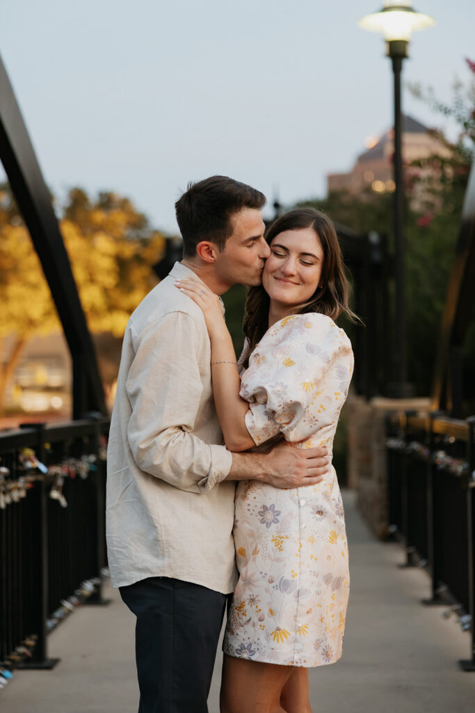 Man kissing his fiancee on the cheek.