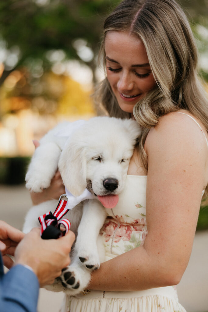 Woman holding a puppy during her surprise proposal.