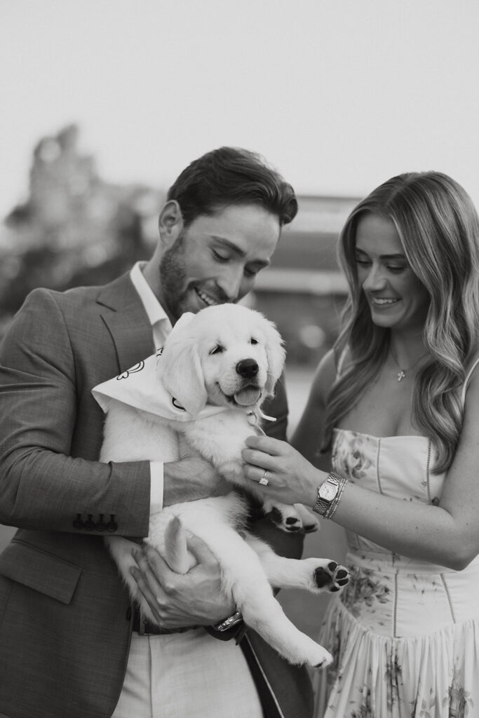Couple smiling while holding their new puppy.